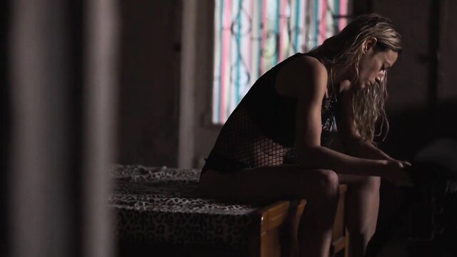 Dimitra Vlagopoulou in sheer black lingerie, sitting pensively