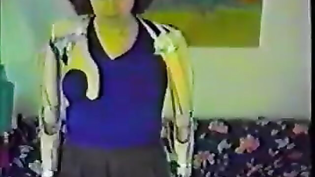 Cynthia Dusel in shiny fetish exoskeleton harness over V-neck top