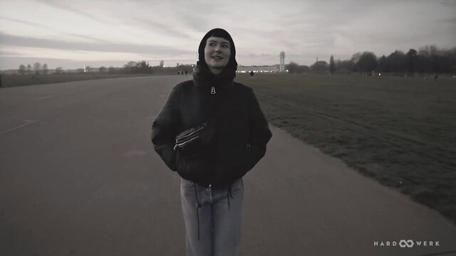 Delfine in black hoodie and fanny pack smiling outdoors at dusk