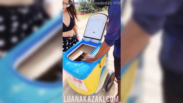 Luana Kazaki with ice cream vendor at beach, opening cooler