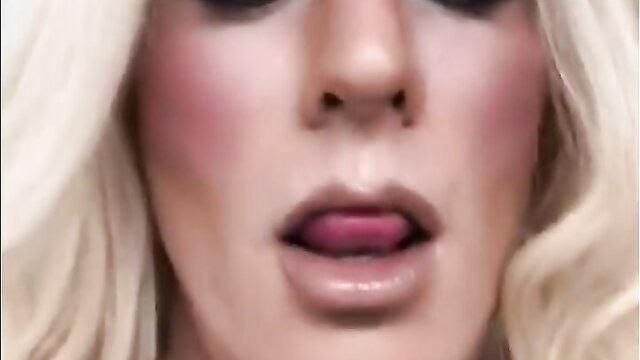 Blonde tgirl closeup with glossy lips and tongue out, heavy makeup