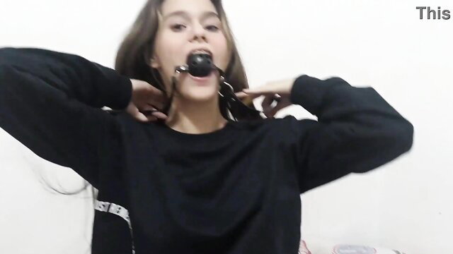 Bored teen stepsister in black hoodie gagged with ball gag, drooling