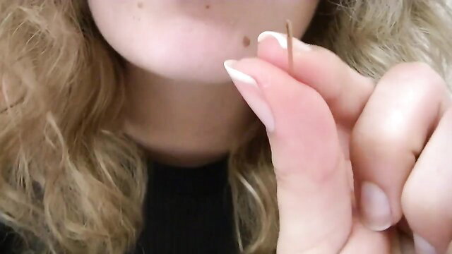 Blonde amateur babe with white nails holding needle near pierced lip closeup