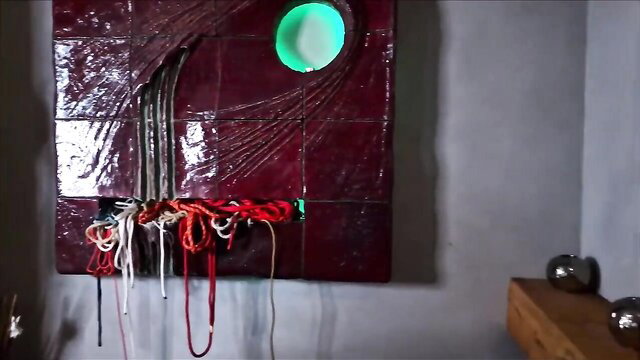 Valentina Love bound in red ropes on erotic glowing art installation