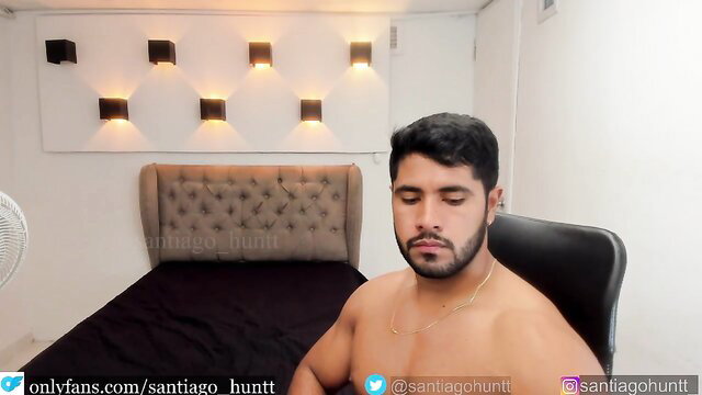 Shirtless Latino hunk Santiago Huntt sits nude in chair, muscular body
