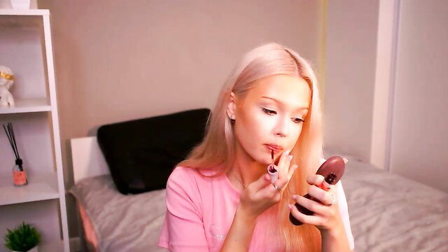 Mirianscorgie applying lipstick in pink top, blonde beauty closeup