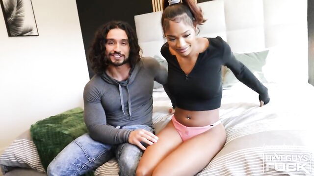 Short king with huge cock sits with ebony supermodel on bed in tight top and panties