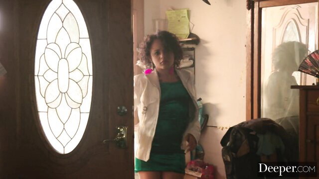 Curvy black woman in green dress and white jacket at door
