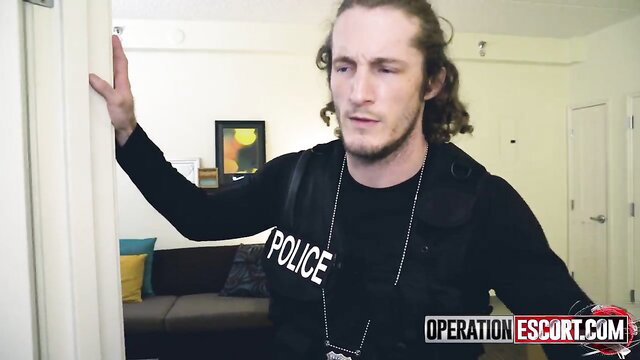 Police officer in tactical gear pins suspect against wall in bust scene