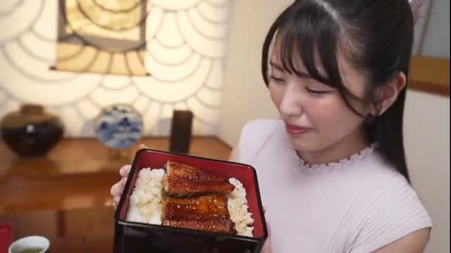 Japanese 出張マッサージ師 holds eel rice bento, smiling cutely