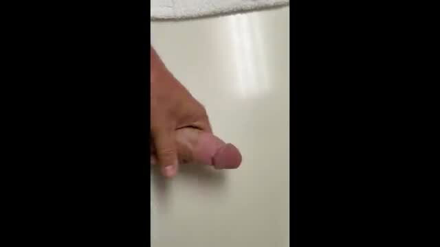 Brown hand stroking pink dildo on wet bathroom floor