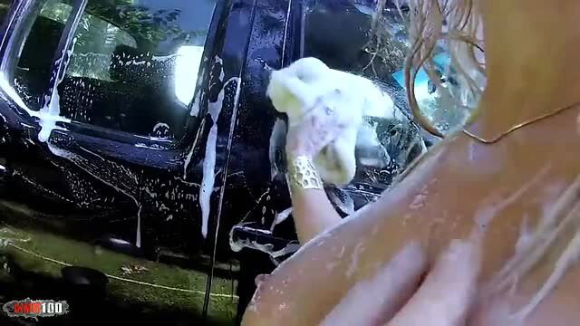 Blonde babe with big tits suds up black car in sexy wet carwash
