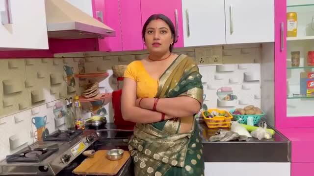 Indian stepmom in saree standing in kitchen, arms crossed