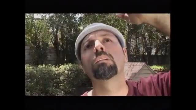 Bearded man in cap outdoors looking up at camera