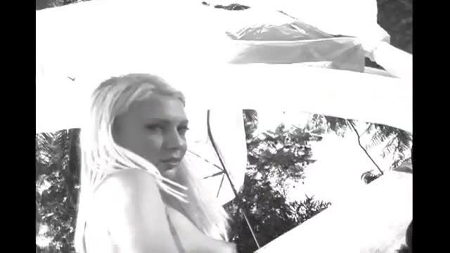 Busty blonde woman topless outdoors under white canopy