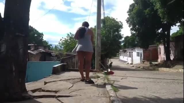 Woman in short dress standing on cracked street, back view