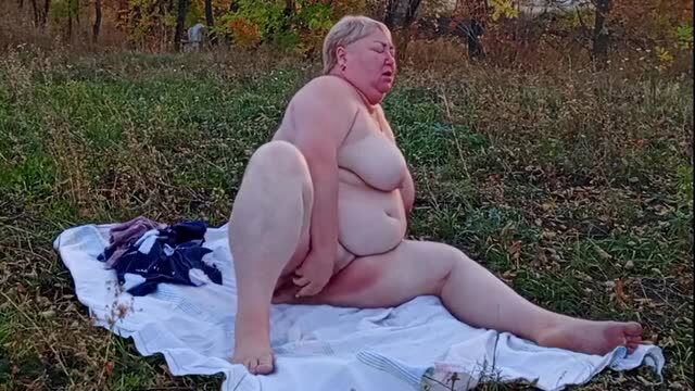 Mature BBW woman masturbating outdoors on blanket in nature