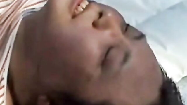 Closeup of obese Asian mature woman's smiling face on bed