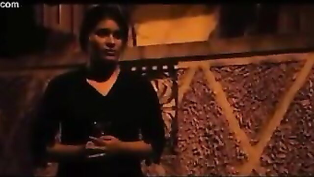 Indian MILF in black v-neck top holding drink in erotic web series scene