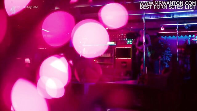 Blurry neon-lit swinger club scene with dancers on pole