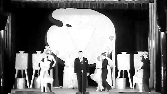 Vintage Hollywood burlesque stage show with tuxedo man and glamorous dancers
