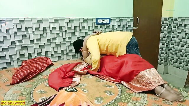 Handsome Indian husband kissing sexy Bengali wife in red saree on bed
