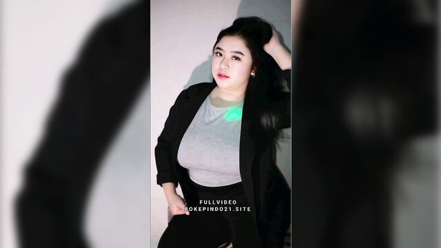 Indo Asian babe in gray top blazer, long black hair, glowing necklace pose