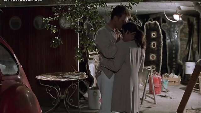 Passionate couple embrace in garage, man kissing woman's neck intimately