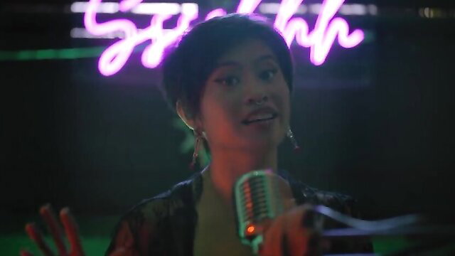 Asian hottie with short hair sings into mic in erotic TV show Sssshhh nude tits tease