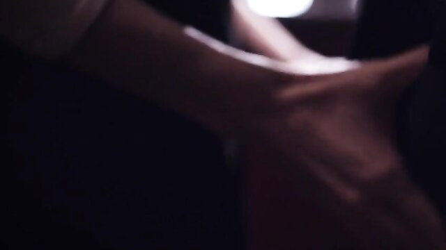 Blurry closeup of woman's arm and hand near man's crotch in dim pub light