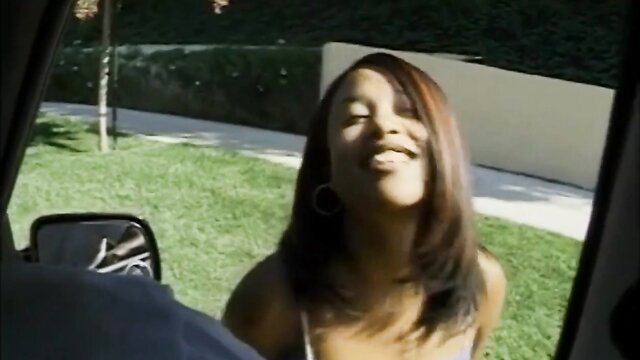 Smiling hairy black teen Aliyah leaning into car window outdoors