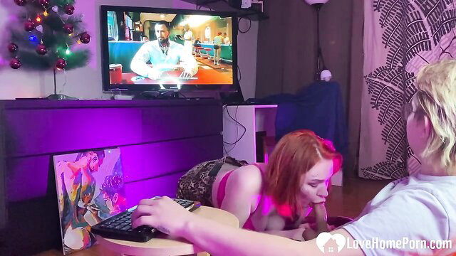 Redhead babe in skimpy lingerie sucks cock while guy watches TV