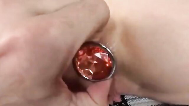Closeup of red jeweled butt plug pulled from girl's ass after blowjob