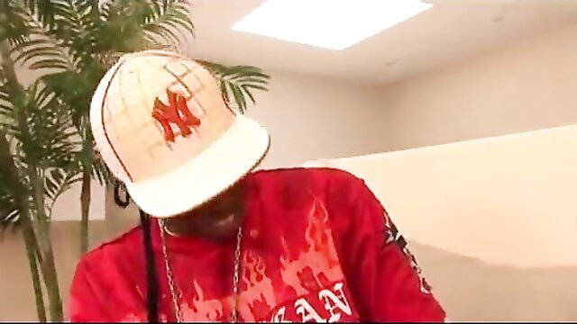 Hot black babe in red flames shirt and M hat poses seductively