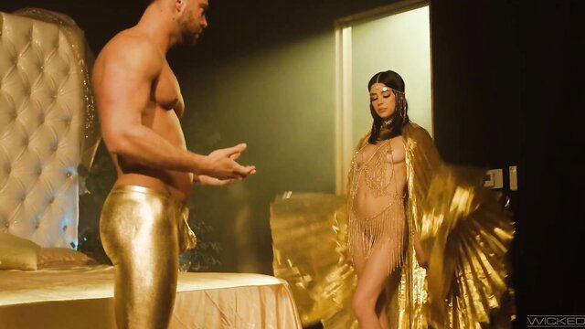 Muscular man in gold pants with busty brunette in gold lingerie