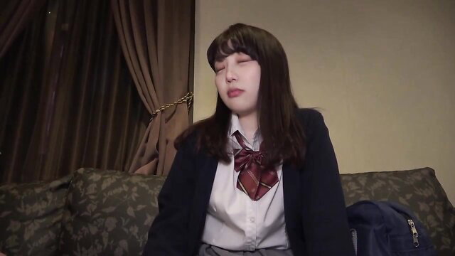 Cute Japanese JAV teen in school uniform sits on hotel couch, amateur style