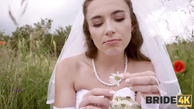 Beautiful brunette bride in white wedding dress holding bouquet outdoors