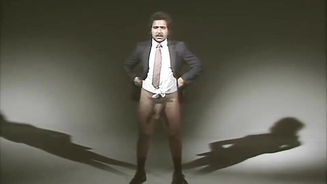 Man in suit and tie exposing bulge, hands on hips pose