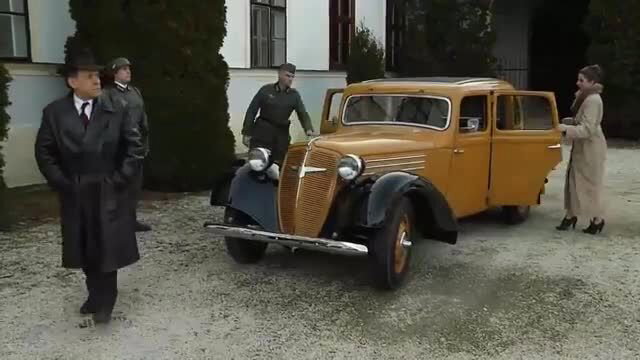 Vintage 1930s yellow car with suited men and elegant woman in fur coat