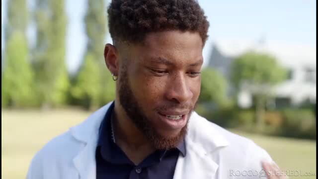 Handsome Black doctor in white coat, closeup outdoor portrait