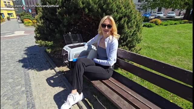 Blonde woman in sunglasses sits on bench with pet carrier outdoors