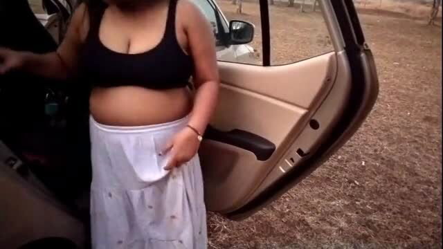 Busty Desi woman in black top and white skirt by car in forest
