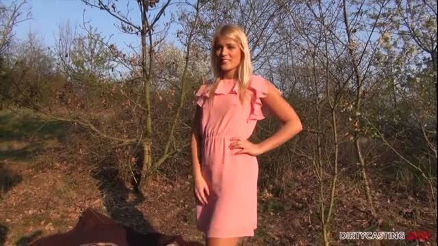 Blonde in pink dress posing outdoors in sunny woods