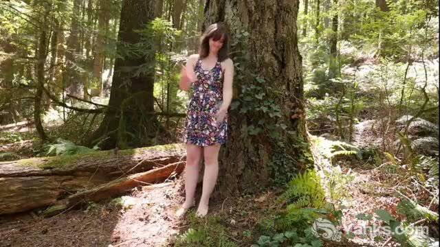 Raven in floral dress masturbating outdoors against forest tree