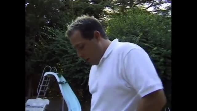 Man in white polo shirt standing by poolside