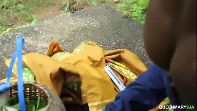 Man in blue shirt bent over sacks and baskets on ground outdoors