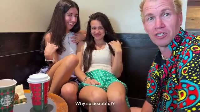Two brunette women sit close in cafe with man in colorful shirt