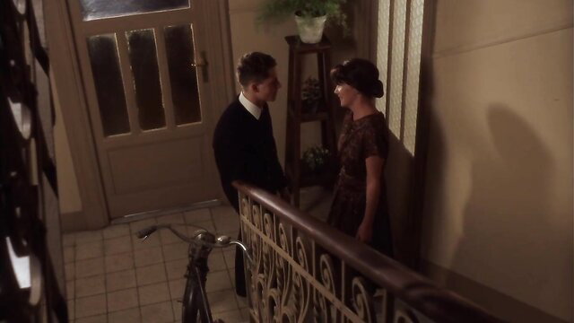 Vintage 1920s couple in alcove, flapper dress and suited man intimate pose