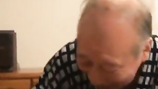 Old Japanese man in checkered shirt gazes down intimately