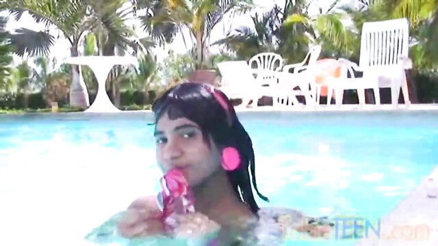 Indian teen vixen in pink headphones sucking toy in pool solo